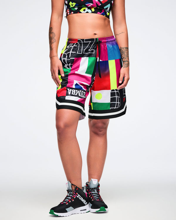 Female model wearing colorful patterned shorts and black sneakers on a white background.