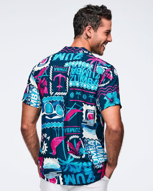 Back view of a navy short-sleeve button-up shirt with an allover teal, white, and hot pink Zumba beach graphic print; shown on a male model with white shorts.