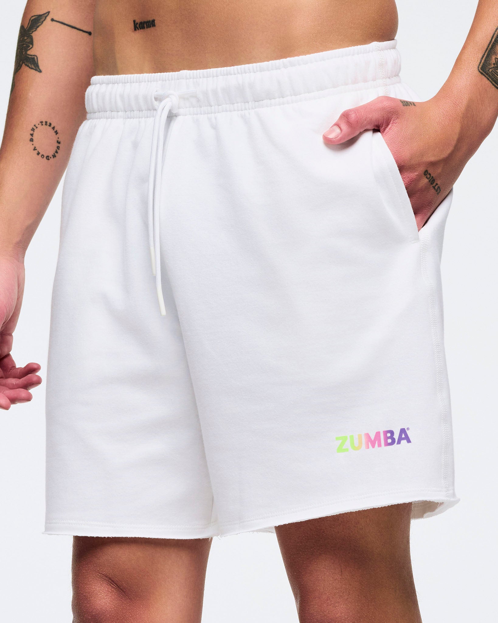Close up of man in white shorts, with small Zumba text on the left leg on a white background.