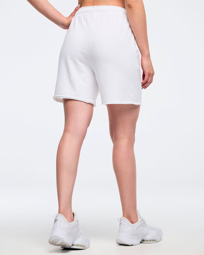 Back view of woman in white shorts on a white background.