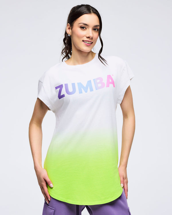 Woman wearing a pastel ombré T-shirt that fades from green at the bottom to white at the top, with “Zumba” spelled in pastel colors across the chest, on a white background.