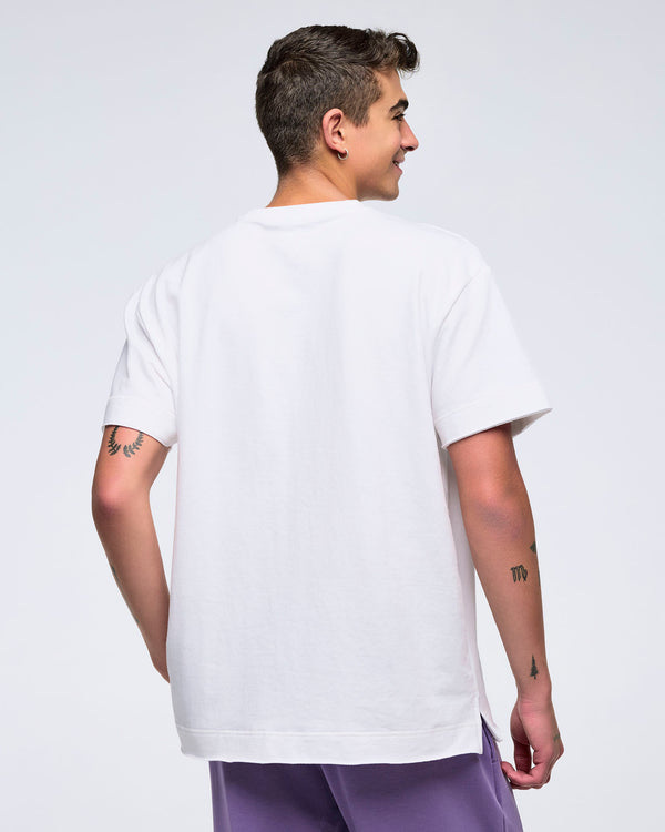 Back view of a man on a white background wearing a plain white T-shirt and purple pants, turned slightly to the side.