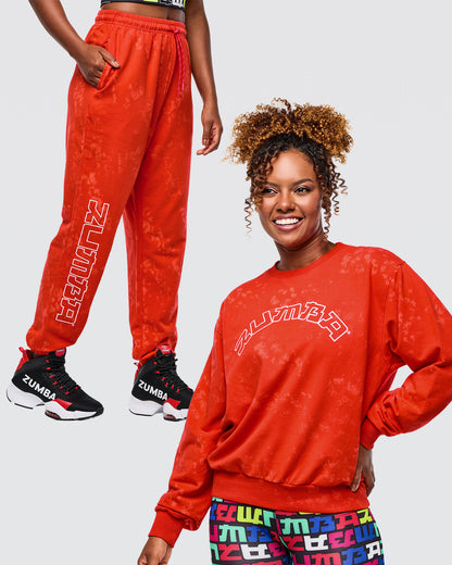 Bundle image of a female model wearing red Zumba sweatshirt and red pants with colorful patterns on a white background