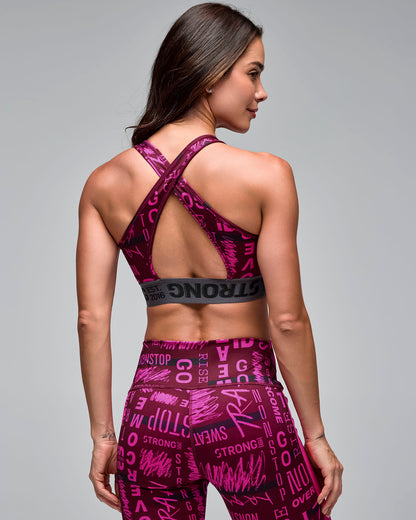 Burgundy and pink graphic-print sports bra with crisscross back straps and a gray elastic under-band, shown from the back on a female model wearing matching high-waisted leggings.