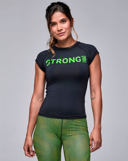 The black fitted muscle top on a female model, with neon green 'STRONG iD' across the chest, worn with neon green and black wavy check print biker shorts.
