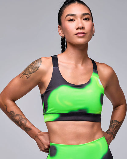 Neon green and black swirl print scoop neck bra on a female model, with black adjustable straps and a black band, paired with matching leggings.