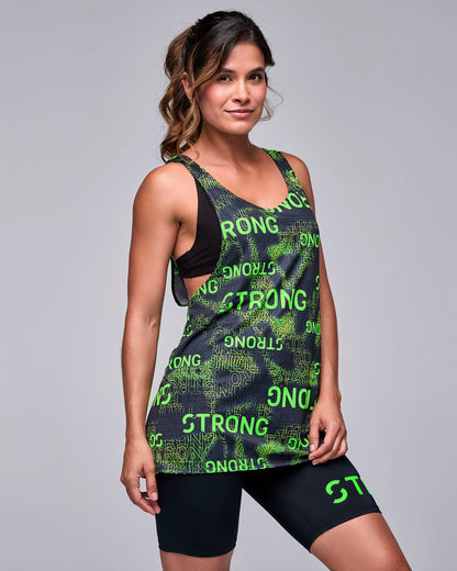 Female model in the black and neon green 'STRONG' print drop armhole tank, shown in side view, with black biker shorts with neon green text.