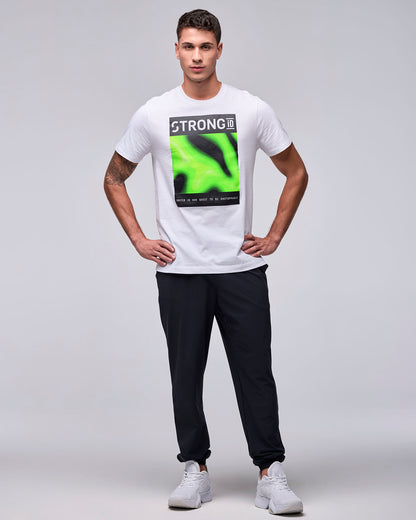 Full view of a male model in the white 'STRONG iD' graphic tee with black joggers and white shoes, hands on hips.