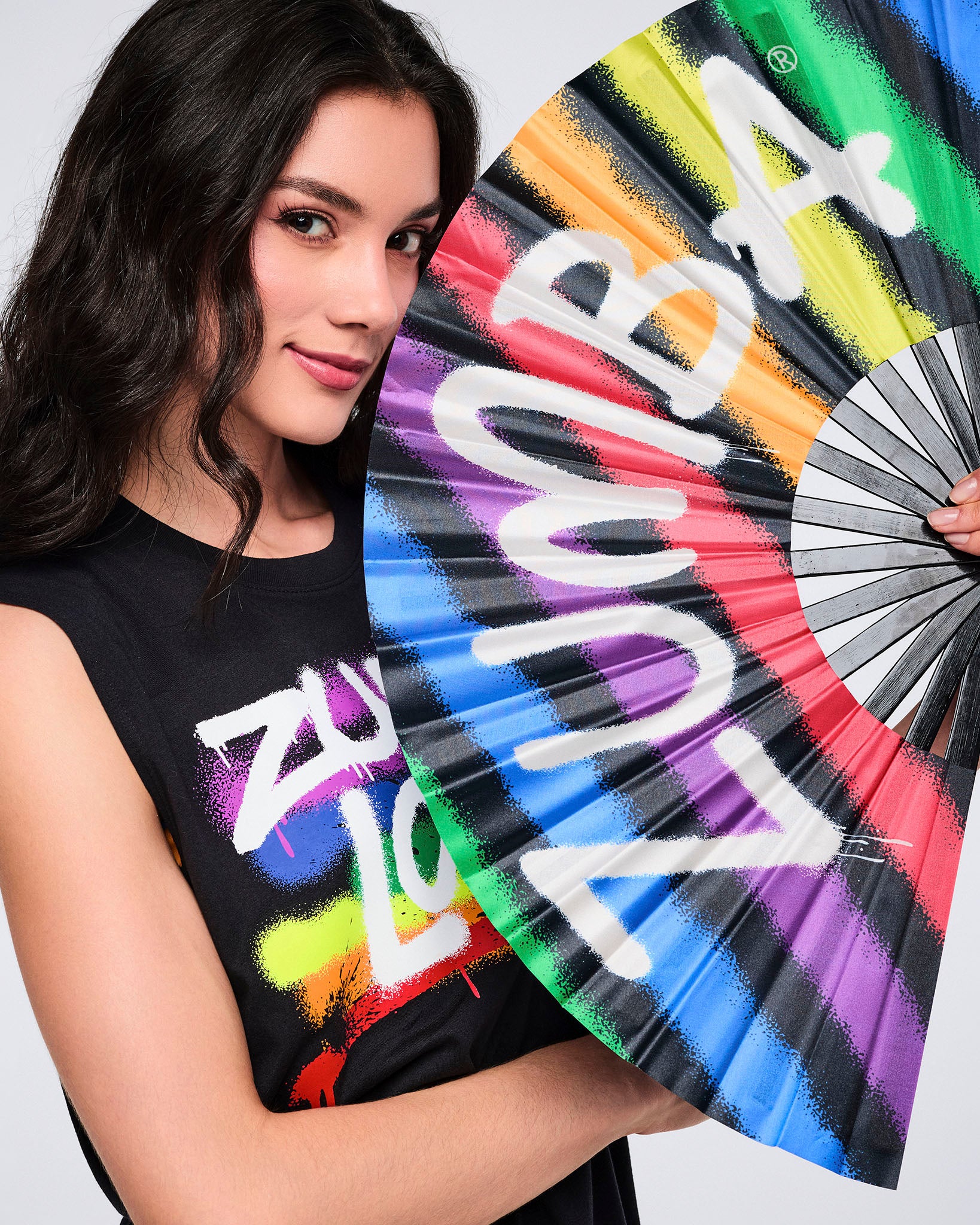Female model holding a colorful hand fan with Zumba text.