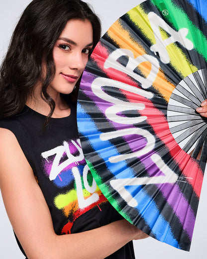 Female model holding a colorful hand fan with Zumba text.