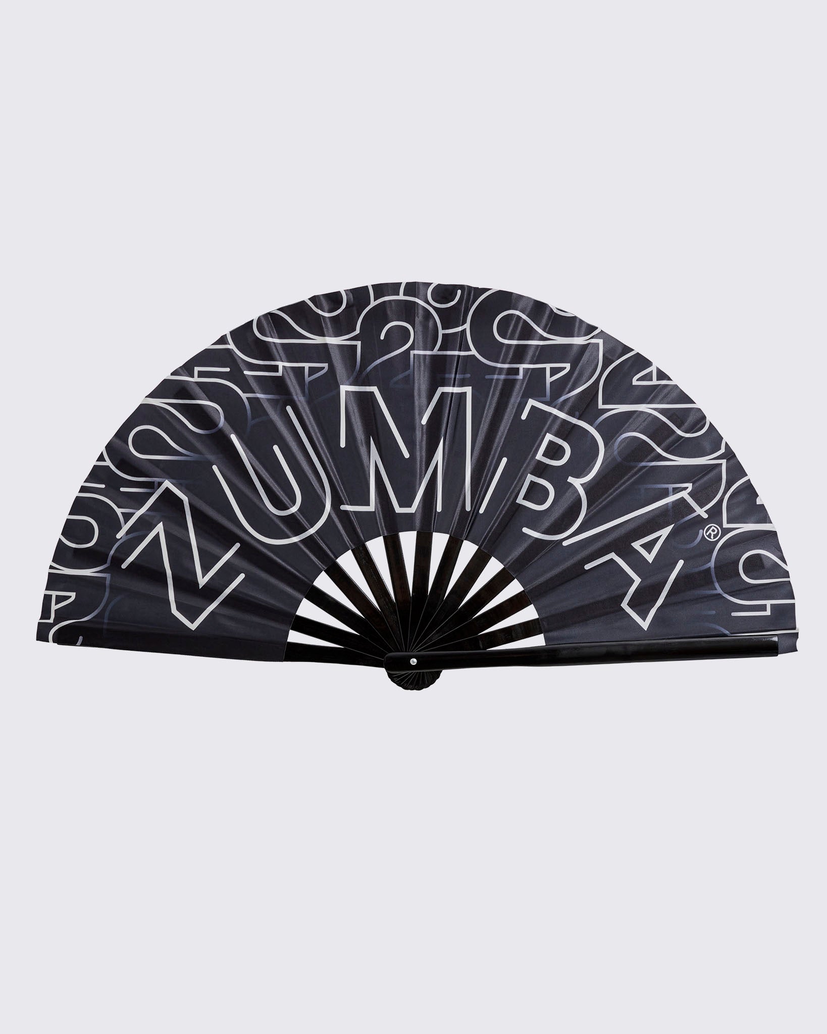 Black folding hand fan with oversized white Zumba lettering and a black handle, shown fully open against a light gray background.