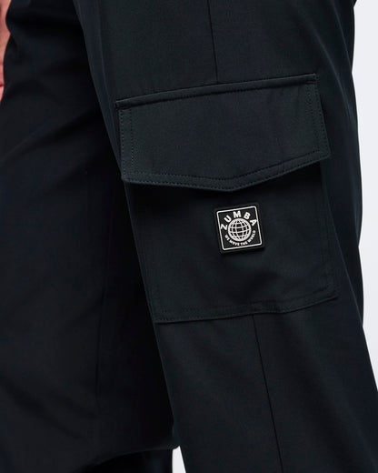 Close-up of the black cargo jogger pants showing the flap cargo pocket and stitched Zumba logo patch on the thigh.