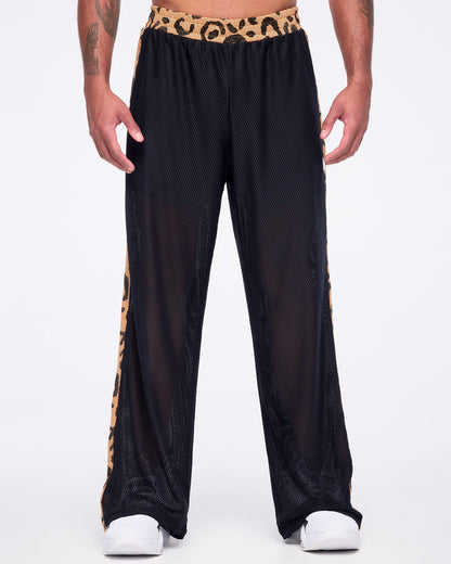 Black mesh wide-leg pants with a sheer finish, tan leopard-print waistband, and matching leopard-print side stripes, shown from the front on a male model wearing white sneakers.