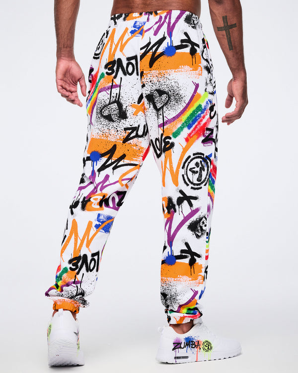 Back view of colorful graffiti-style pants worn by a male model, against a white background.