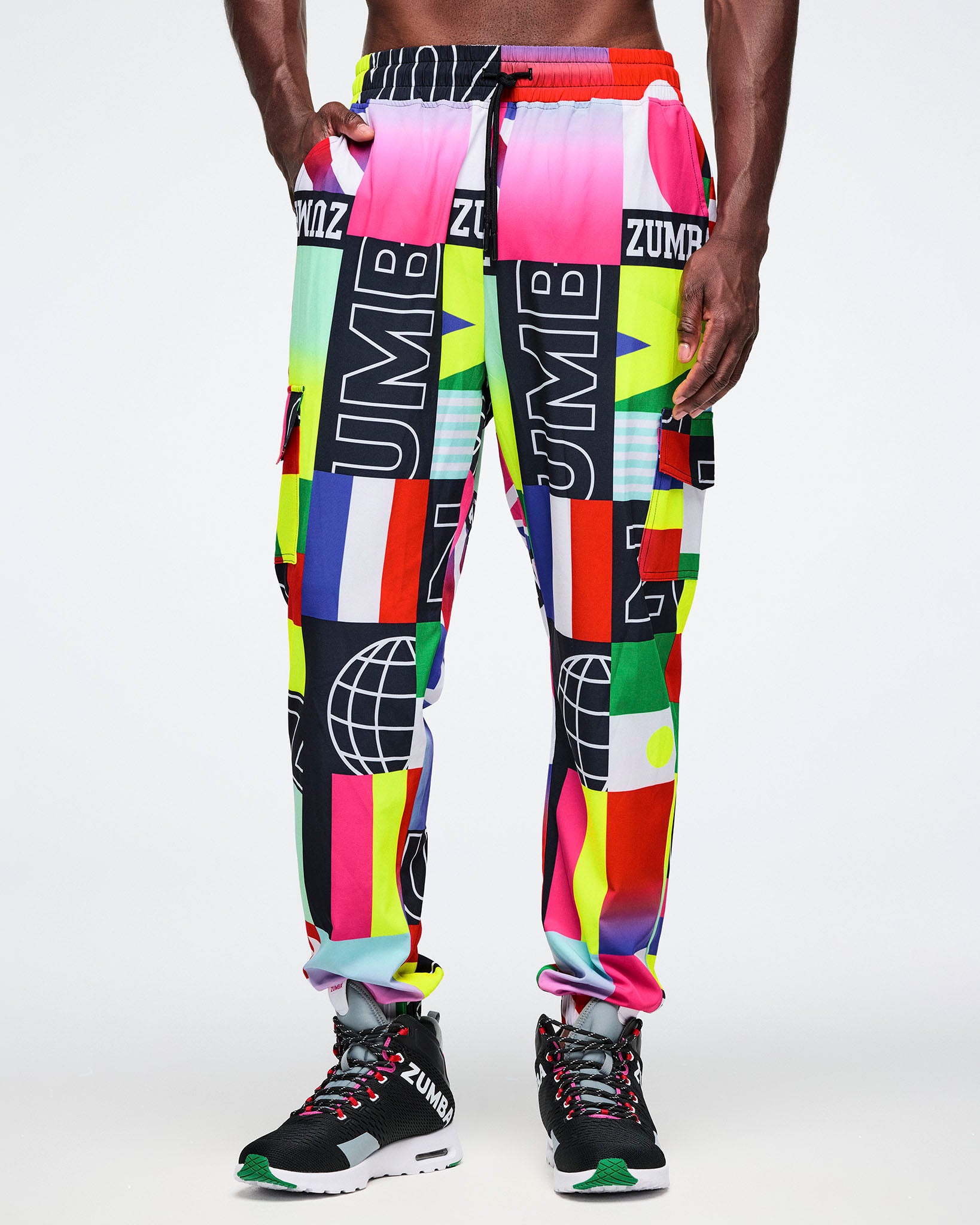Male model wearing multicolored flag patterned pants with 'ZUMBA' branding.