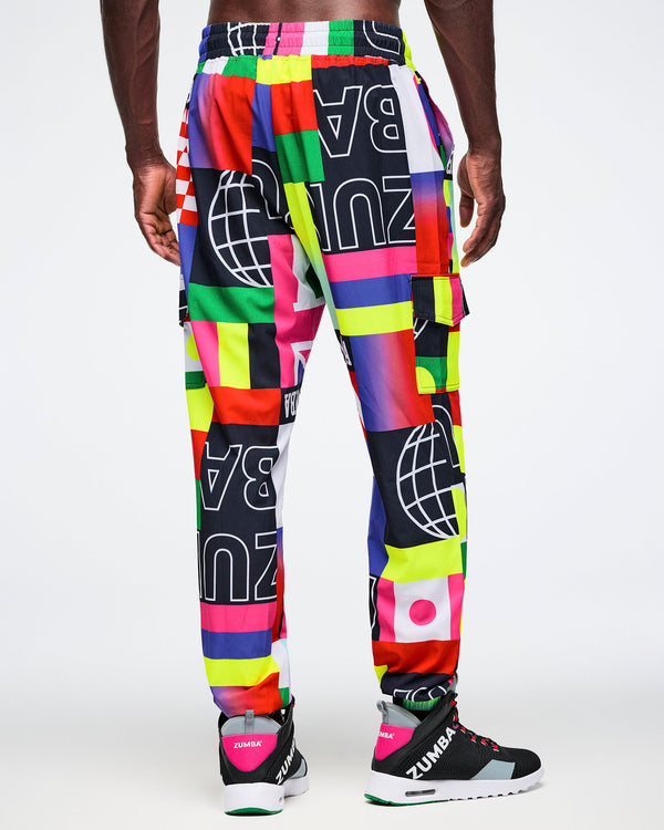 Back view of male model wearing colorful patterned pants with Zumba branding on a white background.