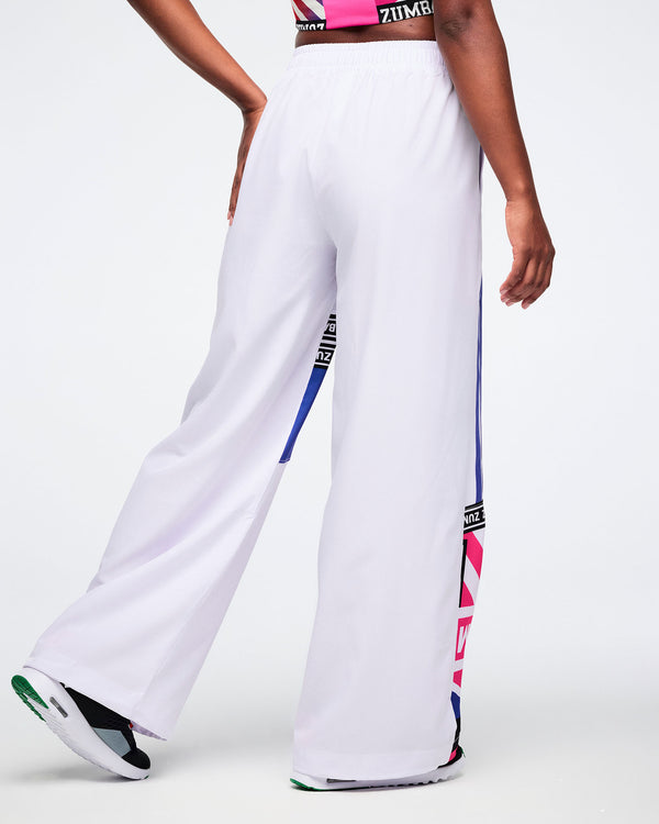Back view of a female model in white wide-leg pants with colorful side panels on a white background.
