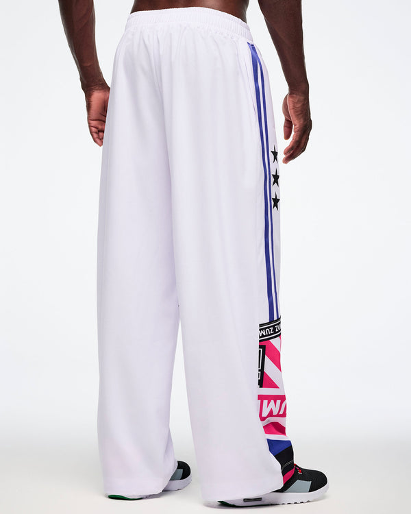 Back view of a male model in white pants with colorful side stripes and Zumba patterns, all on a white backgrounds.