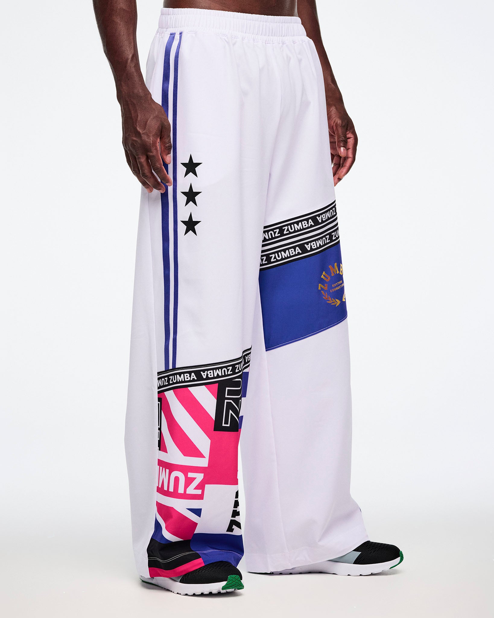 Male model in white Zumba pants with colorful patterns and text on a white background.