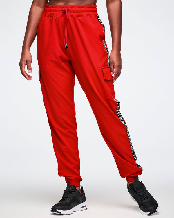 Female model wearing red cargo pants with black and white stripes on a white background.