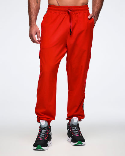 Male model wearing red cargo pants, paired with black and pink shoes on a white background.