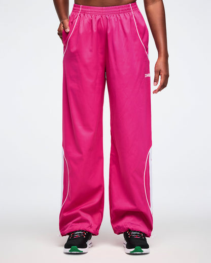 Female model wearing bright pink pants with white accents on a white background.
