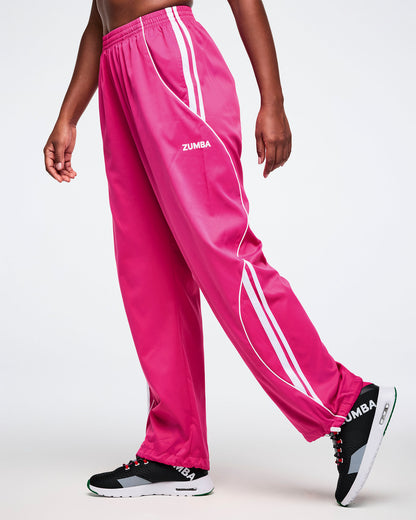 Female model wearing pink Zumba pants with white stripes on a white background.