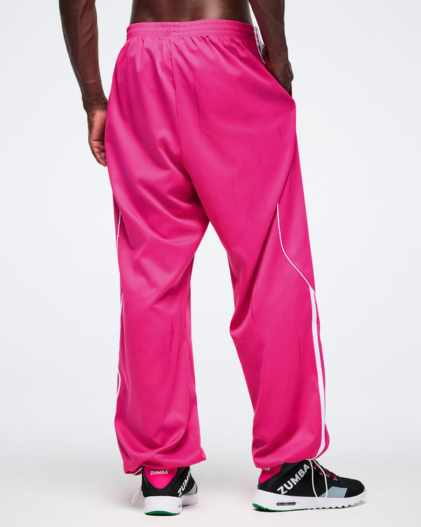 Back view of male model wearing bright pink Zumba pants with a white background.