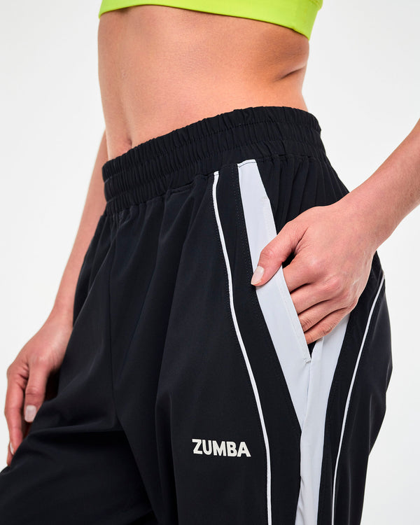 Close-up of a hand in the side pocket of black joggers with a white stripe and 