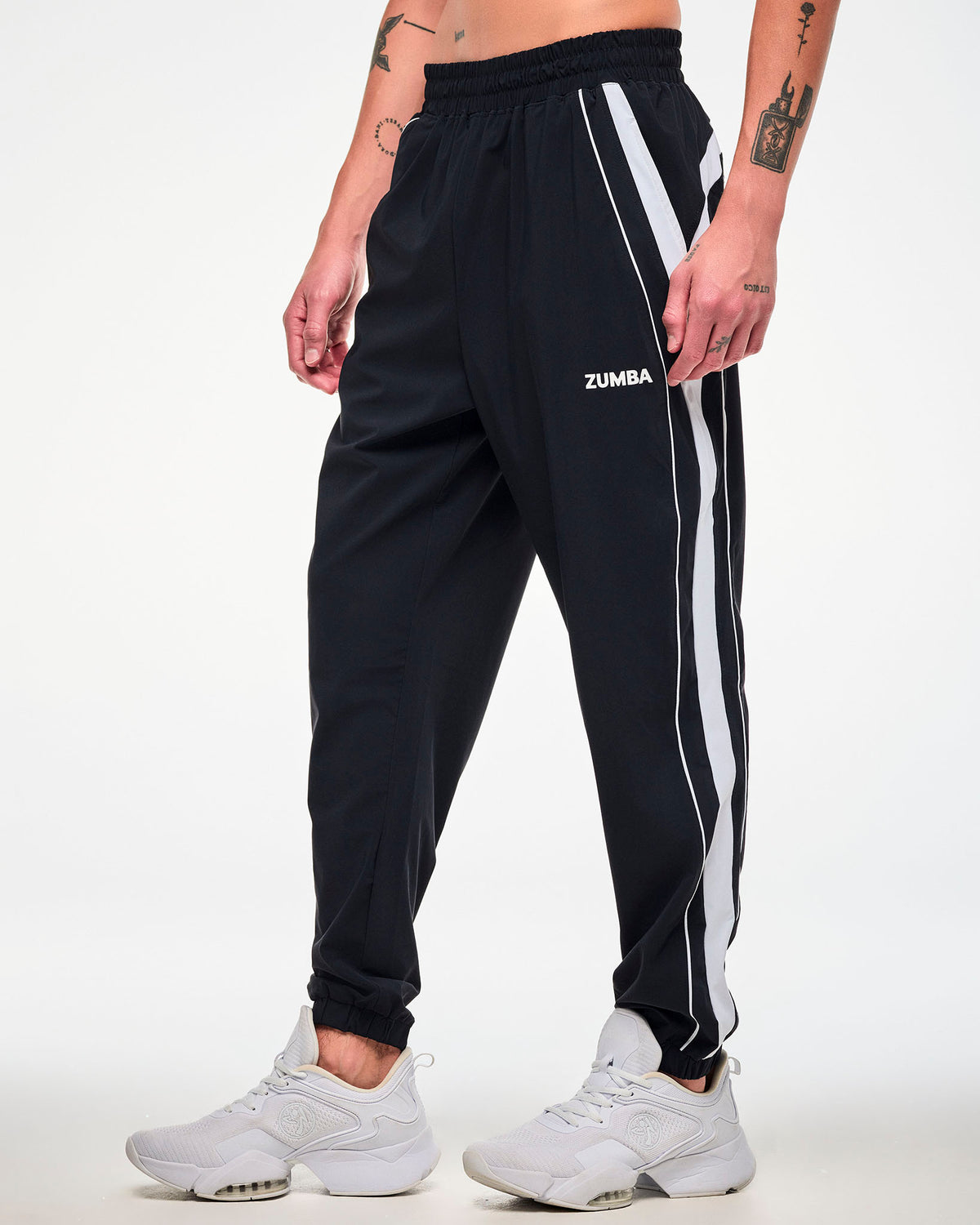 Male model wearing black joggers with a white side stripe, "ZUMBA" text, and white shoes.