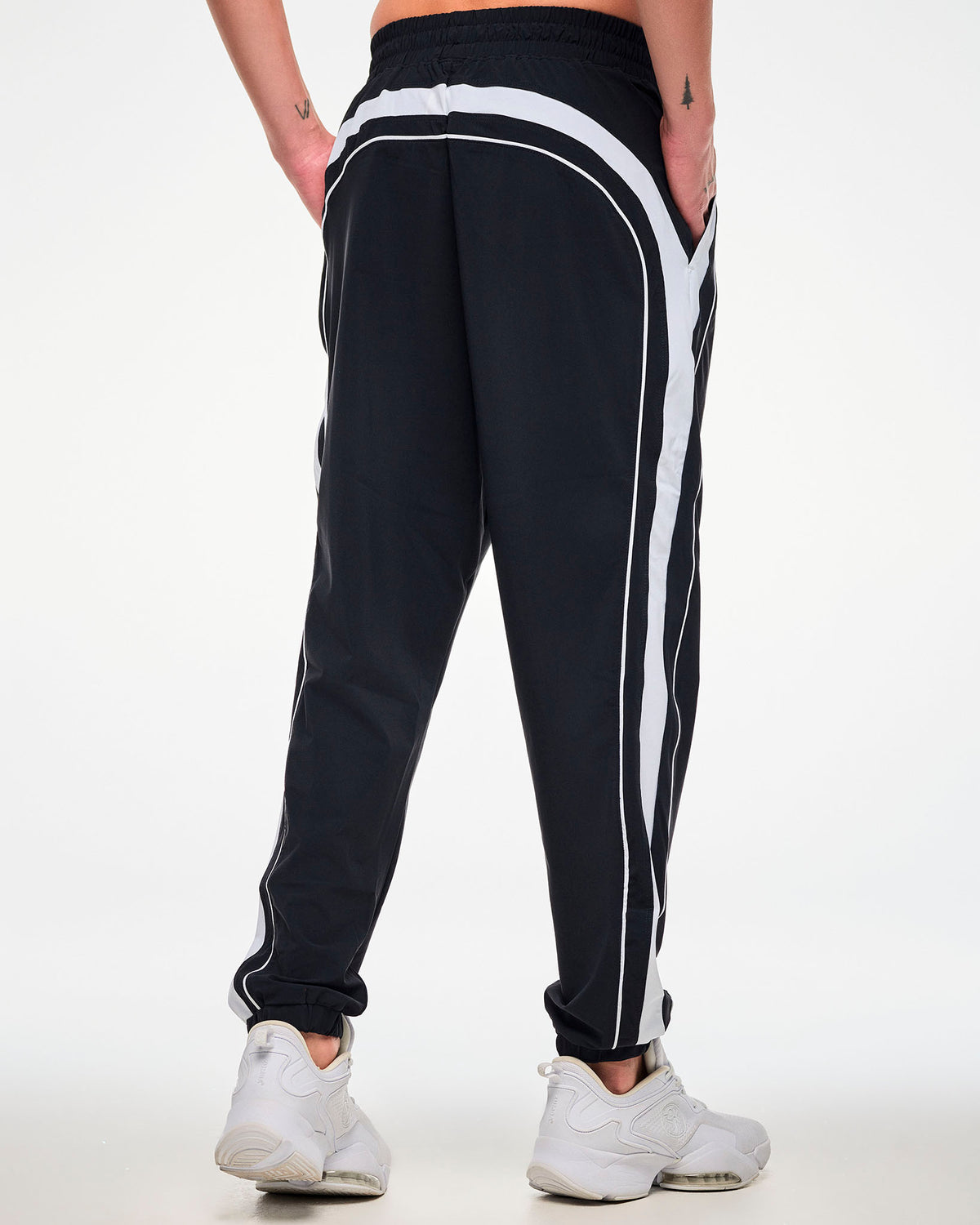 Shown from the back, male model wearing black joggers with a white side stripe, hand in the side pockets.