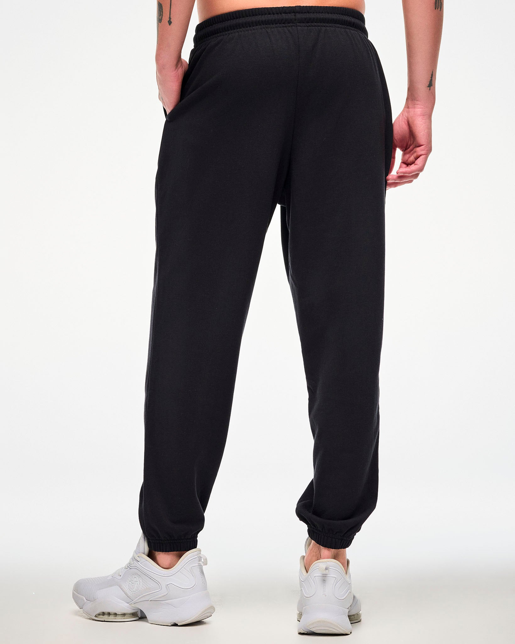 Shown from the back, male model wearing black joggers and white sneakers.