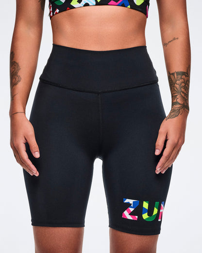 Female model wearing athletic biker shorts with colorful 'ZUMBA' branding on a white background.
