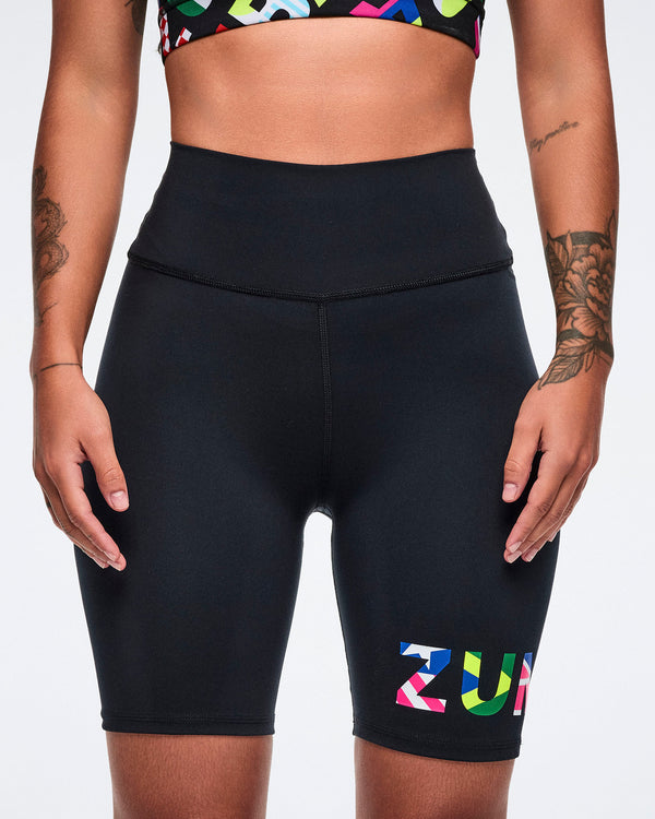 Female model wearing athletic biker shorts with colorful 'ZUMBA' branding on a white background.