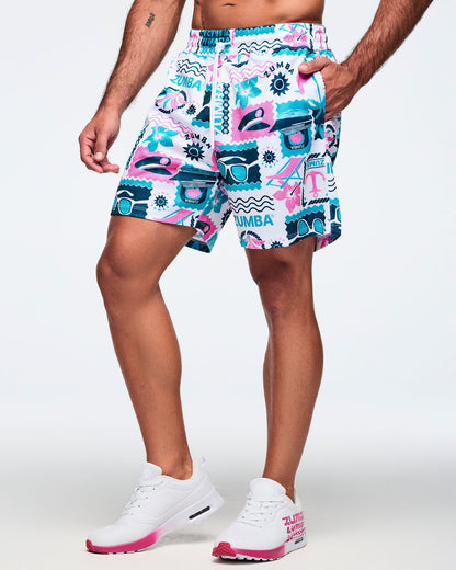 White elastic-waist drawstring shorts with a teal-and-pink allover Zumba beach print and loose fit; shown on a male model with white sneakers with hot-pink soles.