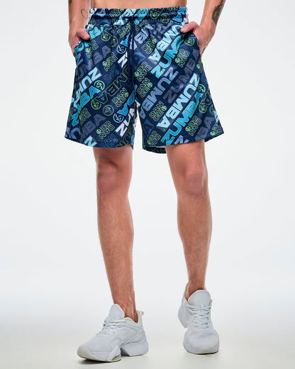 Front view of a male model wearing blue patterned shorts with both hands in his pockets and paired with white shoes.