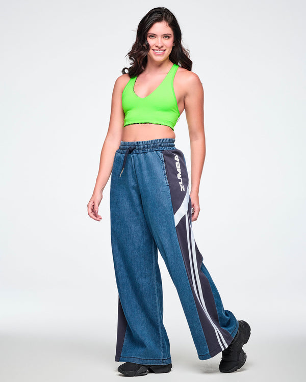 Female model wearing a neon green bra top with wide-leg combo pants featuring a navy side panel, white 