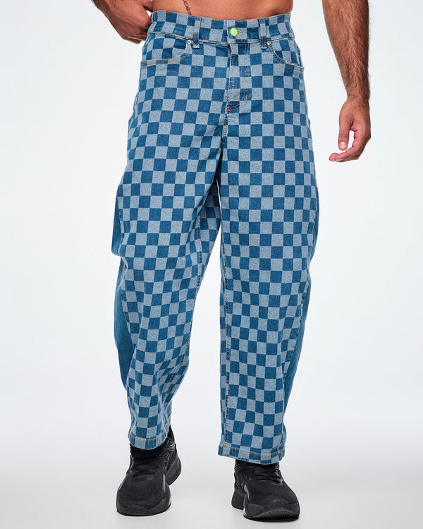 Male model in denim barrel ankle pants with a light and medium blue checkerboard pattern, a lime green front button and paired with black shoes.
