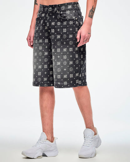 Male model wearing black denim jorts featuring patterned ZW, “01,” stars, dots, and Zumbito motifs, paired with white shoes.