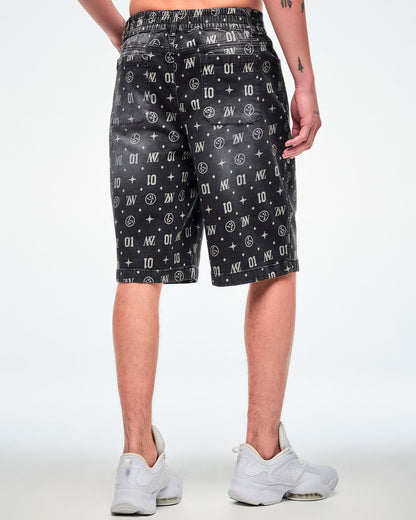 Back view of a male model wearing black denim jorts, showcasing two functional back pockets and patterned ZW, “01,” stars, dots, and Zumbito motifs, paired with white shoes.