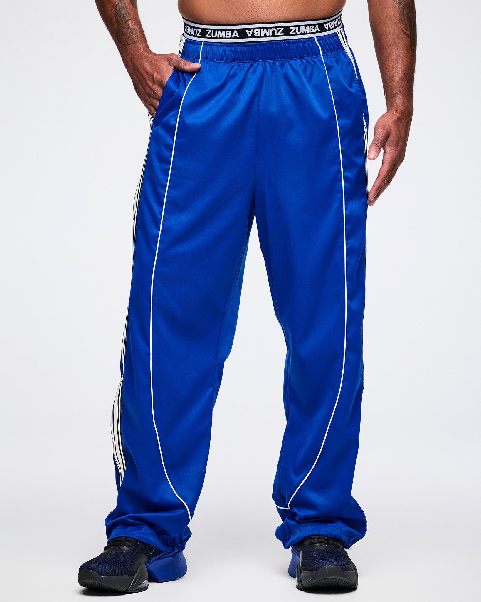 Male model with one hand in his right pocket of the blue woven pants, paired with blue-and-black shoes.
