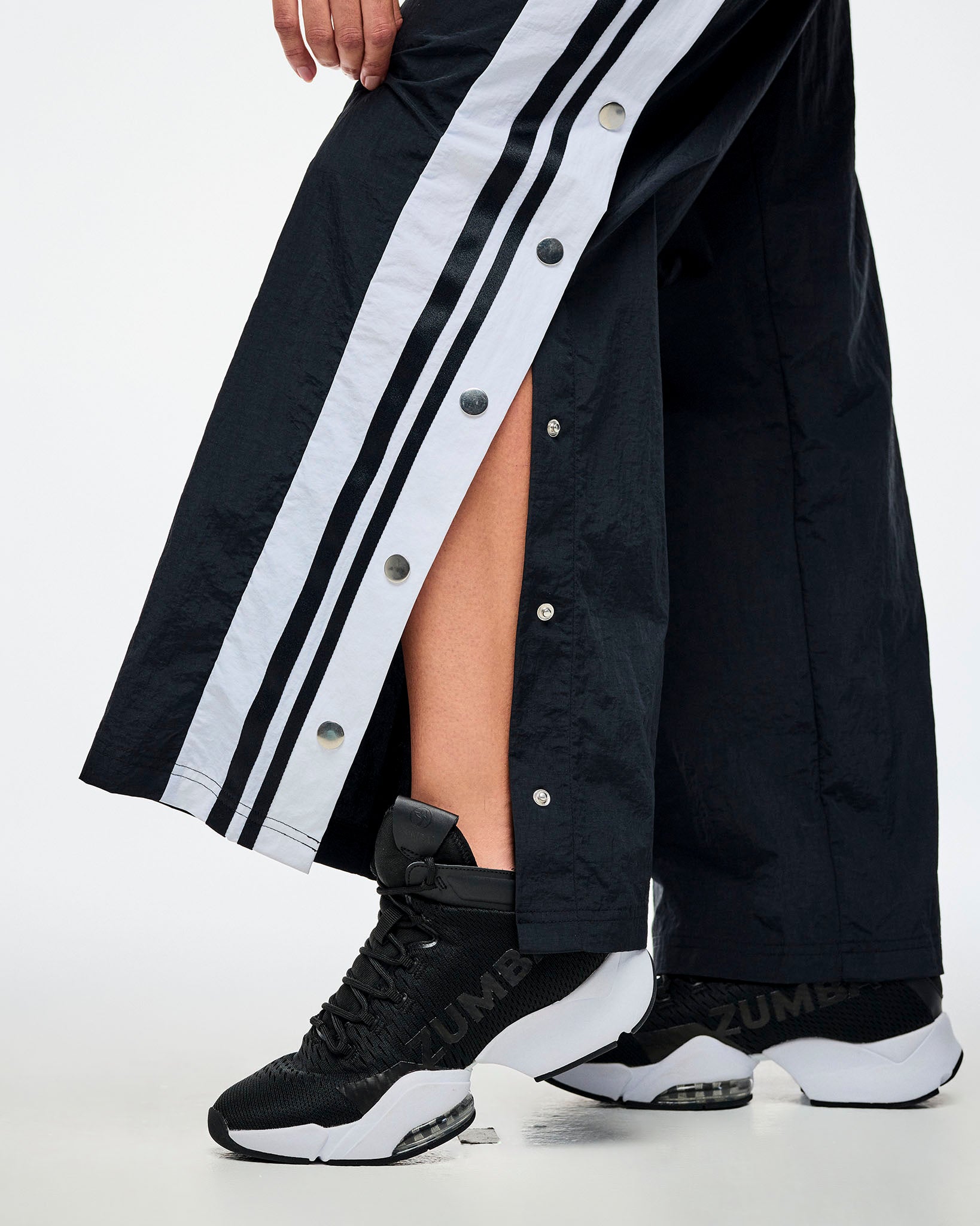 Detailed close-up view of black and white pants with the side snap buttons in detail and paired with black and white shoes.