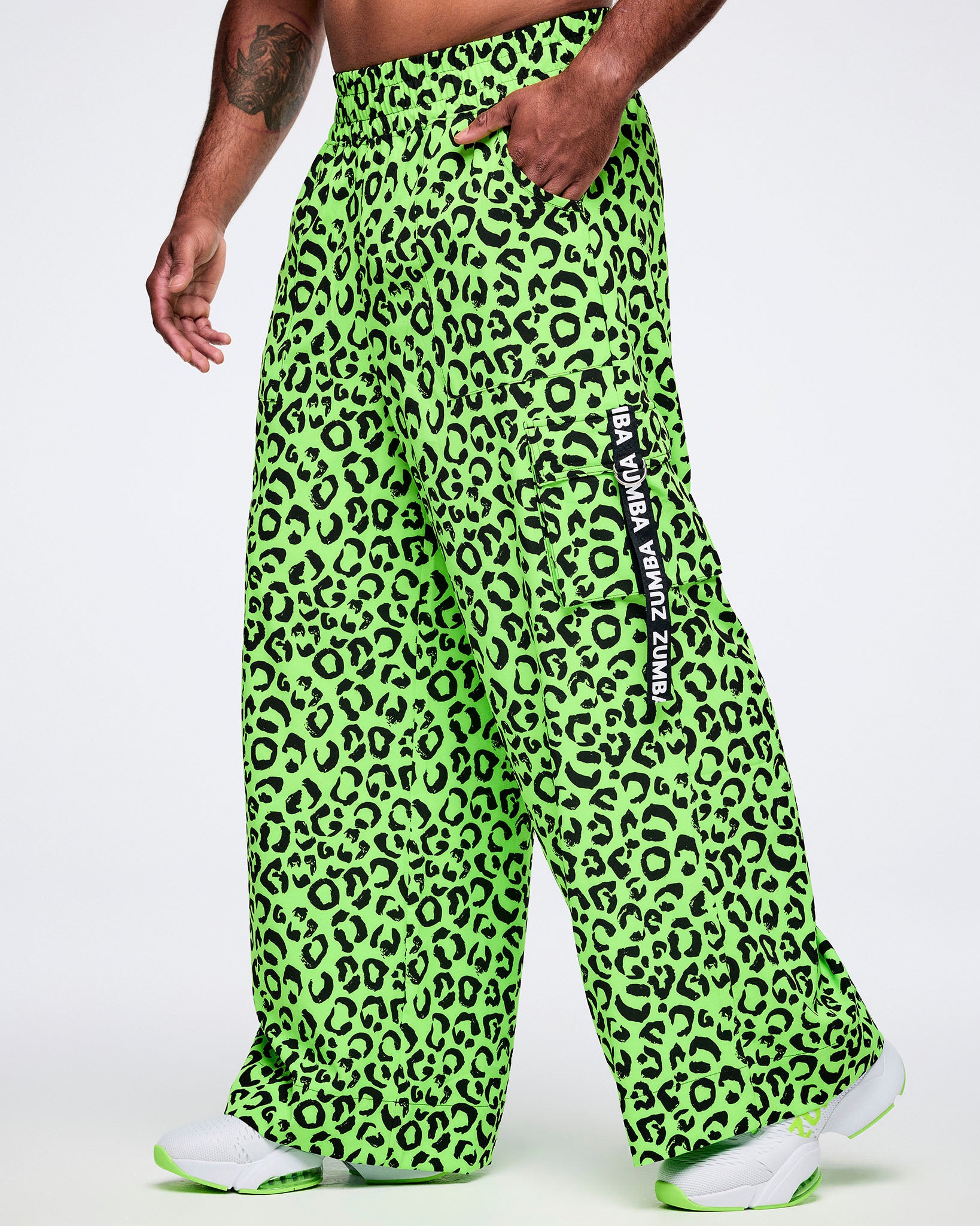 Male model wearing bright green leopard print pants with a visible brand logo on a white background.