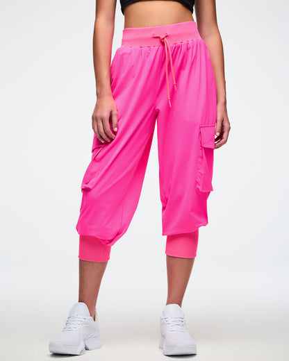 Front view of a female model wearing bright pink cargo pants on a white background.