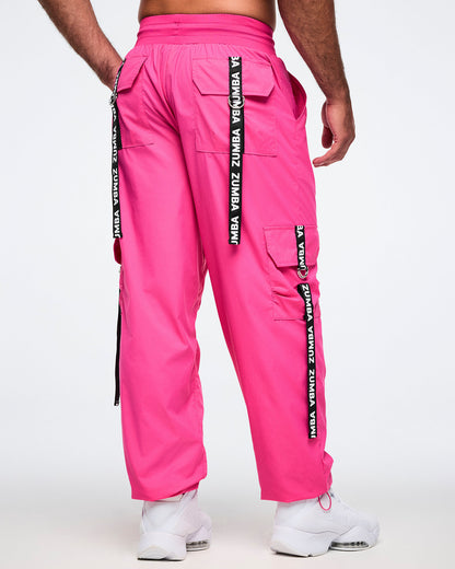 Back view of the pink cargo pants with white'Zumba' branding on the back ribbons on each pocket, worn by a male model.