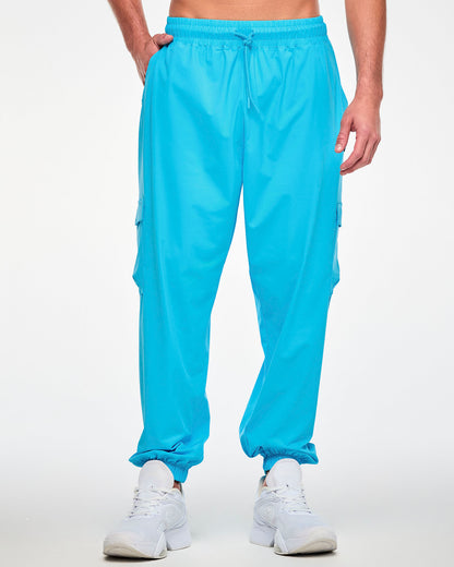 Male model in the aqua blue cargo pants with an elastic drawcord waist and elastic ankle cuffs, one hand in the pocket. Paired with white shoes.