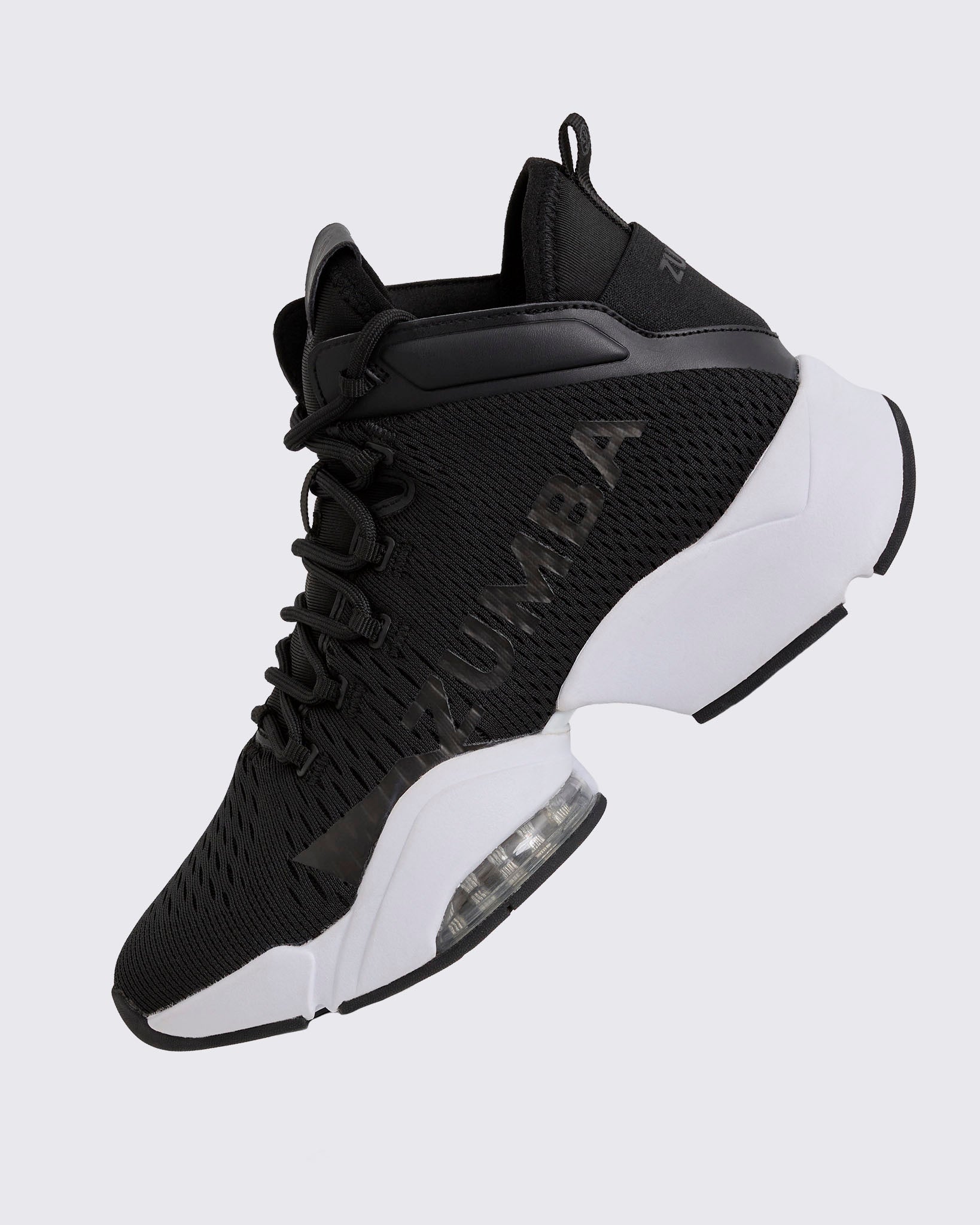 Black Zumba high-top athletic sneaker shown in a side angle, featuring a breathable mesh upper, tonal lace-up closure, glossy black Zumba logo, and chunky white split sole with a visible air cushion.