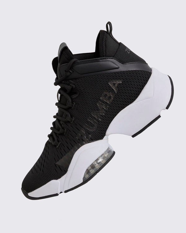 Black Zumba high-top athletic sneaker shown in a side angle, featuring a breathable mesh upper, tonal lace-up closure, glossy black Zumba logo, and chunky white split sole with a visible air cushion.