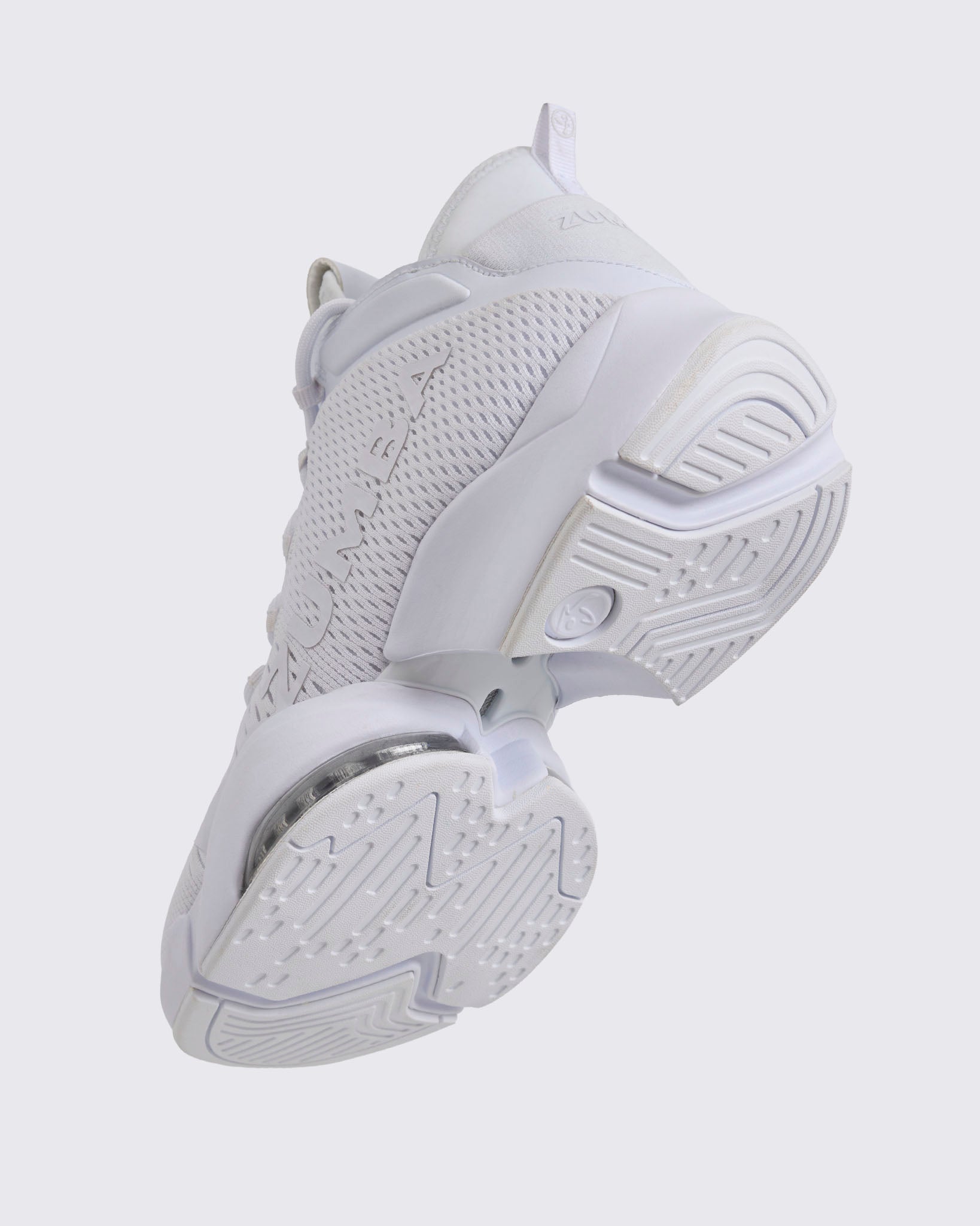 White Zumba high-top athletic sneaker shown from the bottom angle, highlighting the textured outsole tread, split sole design, and visible air cushioning under the mid foot.