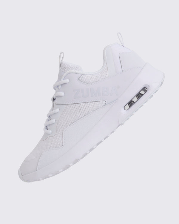 White Zumba low-top athletic sneaker shown in a side angle, featuring a breathable mesh upper, tonal lace-up closure, embossed Zumba logo, and chunky white sole with visible air cushioning.